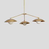 Elegant brass chandelier with three dome-shaped shades and globe bulbs, perfect for modern dining or living room lighting.