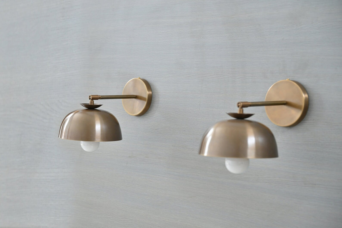 Modern brass dome shade wall sconces installed on wall – angled front view