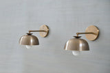 Modern brass dome shade wall sconces installed on wall – angled front view