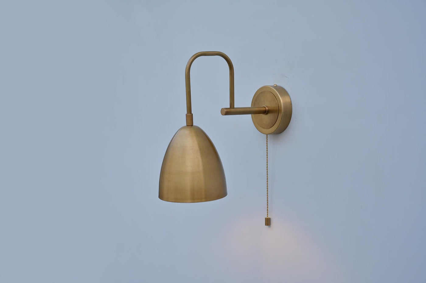 Side view of brass dome wall light with pull chain, handcrafted by Brass Leaf Studio in brushed brass finish for modern interiors.