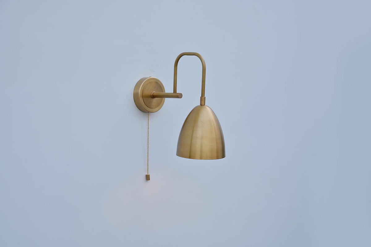 Elegant brass dome wall light featuring a smooth brushed brass shade and pull chain switch, ideal for bedrooms or hallways.