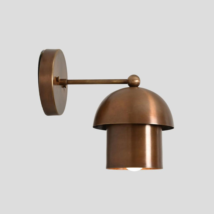 Solid brass dome wall light with cylindrical base and warm ambient glow