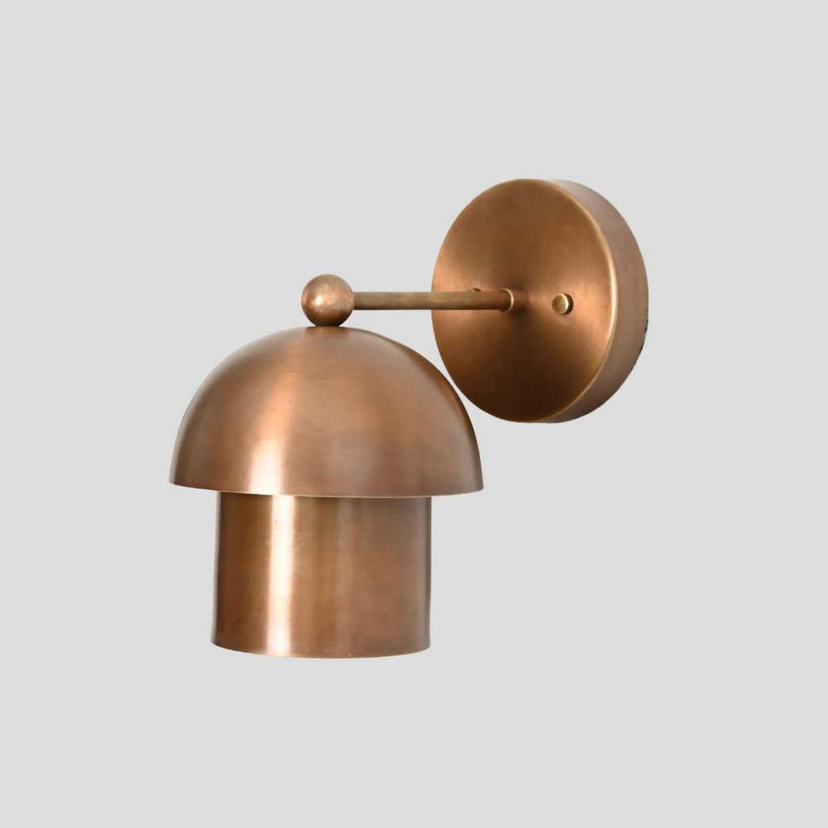 Side view of handcrafted brass dome wall sconce with minimalist round base