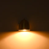 A dome-shaped wall sconce lamp with a dark metallic finish, glowing with a warm yellow light against a dark background.