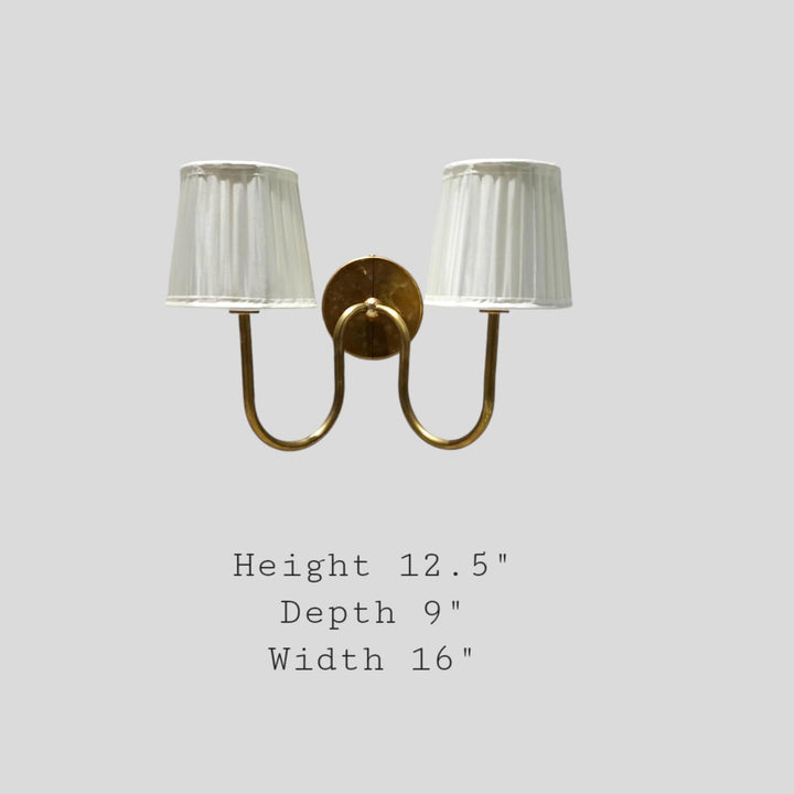 Brass double arm wall sconce with pleated fabric shades showing dimensions – 16 inch width, 12.5 inch height, 9 inch depth