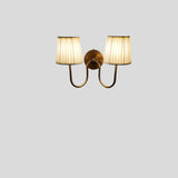 Minimalist brass double arm wall sconce with pleated shades against plain background