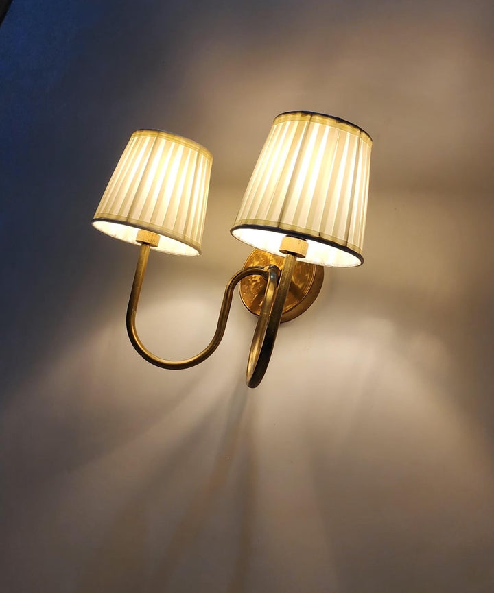 Side view of brass double arm wall sconce with pleated fabric shades
