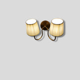 Top angled view of brass wall sconce with two pleated fabric shades
