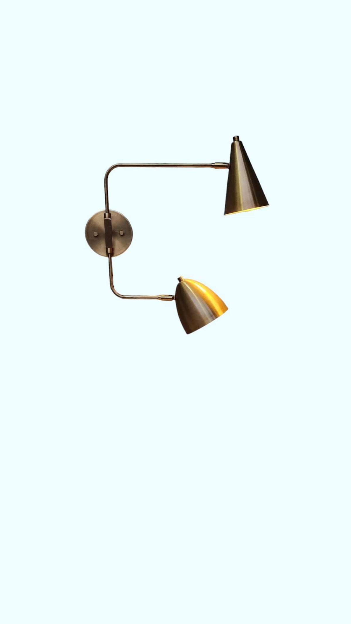 Brass wall sconce with dual cone shades glowing warmly – ambient lighting