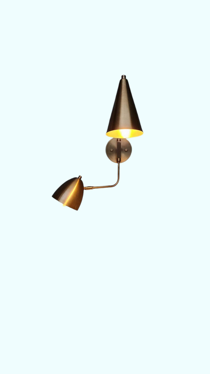 Brass wall sconce with dual cone shades illuminated – warm ambient glow