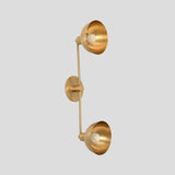 Side perspective of brass double wall sconce with two round shades and slim connecting rod, industrial modern handmade lighting fixture.