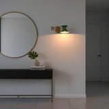 Closeup of brass enamel shade wall light showing green hourglass shade, brass band, and arm detail