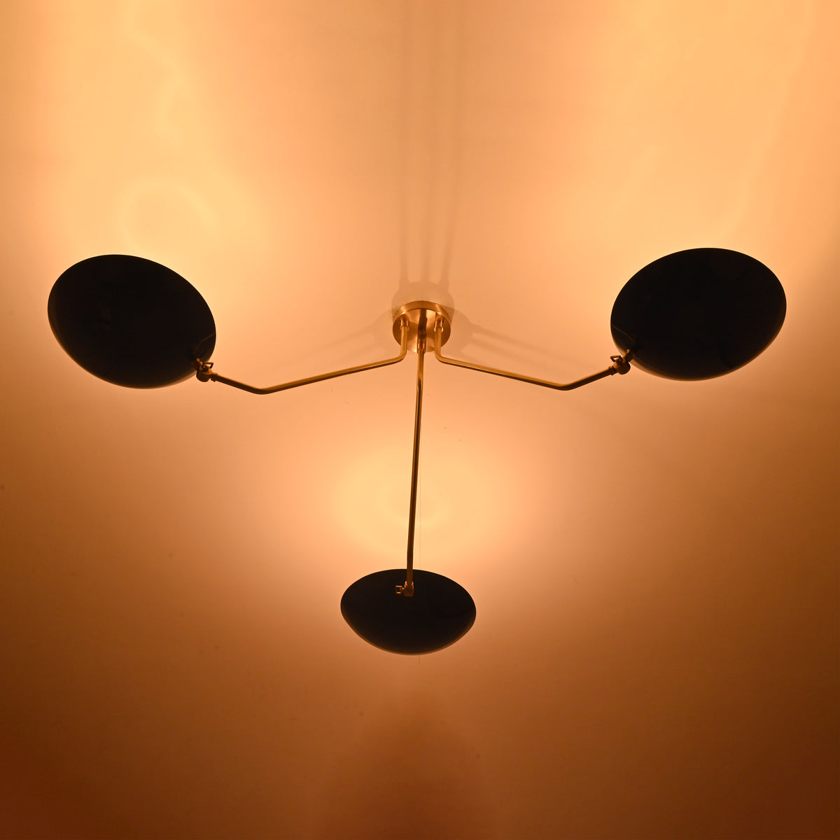 Three-light brass flush mount ceiling light creating warm ambient indirect lighting on ceiling