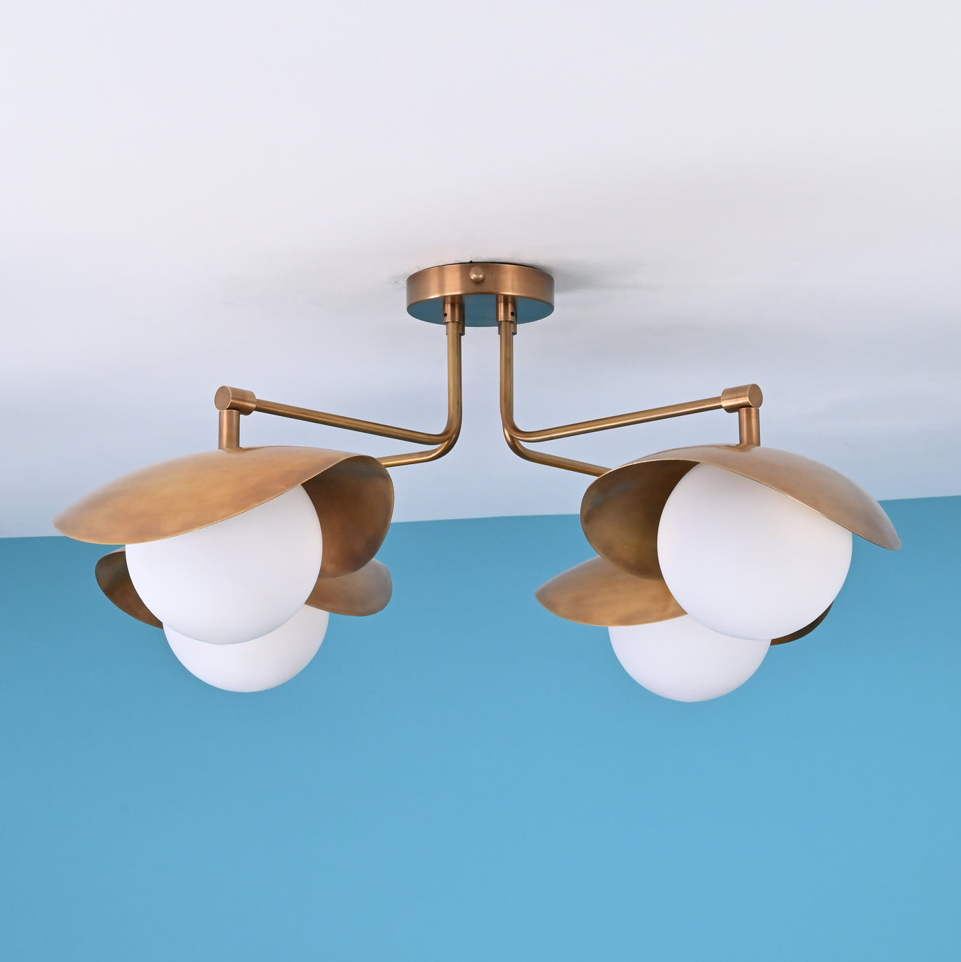 Modern brass flush mount ceiling light with three sculpted dome shades and frosted glass globes.