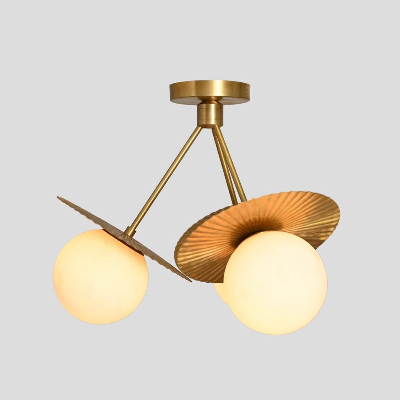 Side view of brass flushmount chandelier with three frosted globe bulbs and sculpted fluted disc shades, minimalist handmade brass ceiling fixture.