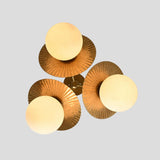 Overhead angle of brass flushmount chandelier with three globe bulbs surrounded by fluted brass shades, elegant modern ceiling lighting.