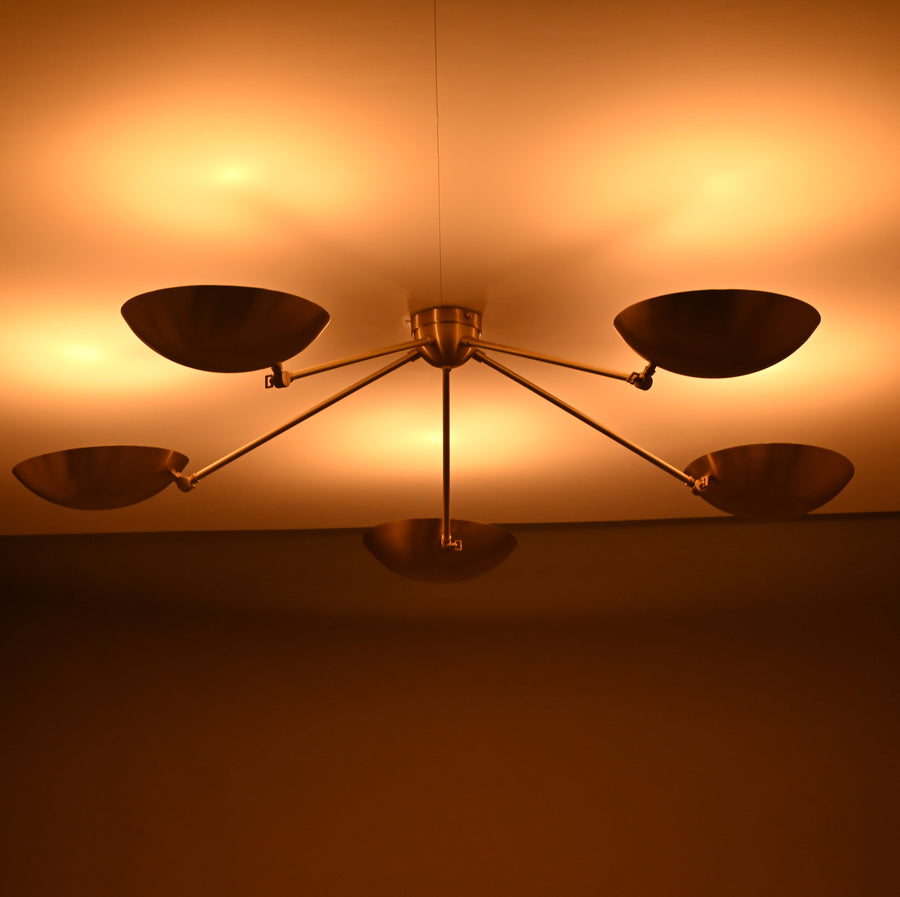 Modern brass flushmount chandelier with five bowl-shaped shades designed for warm ambient ceiling lighting.