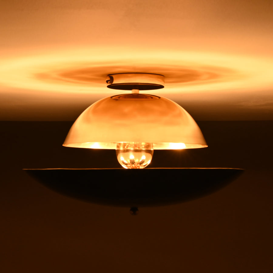 Front view of mixed-finish brass flushmount light with polished brass dome and blackened lower bowl, creating warm indirect illumination.