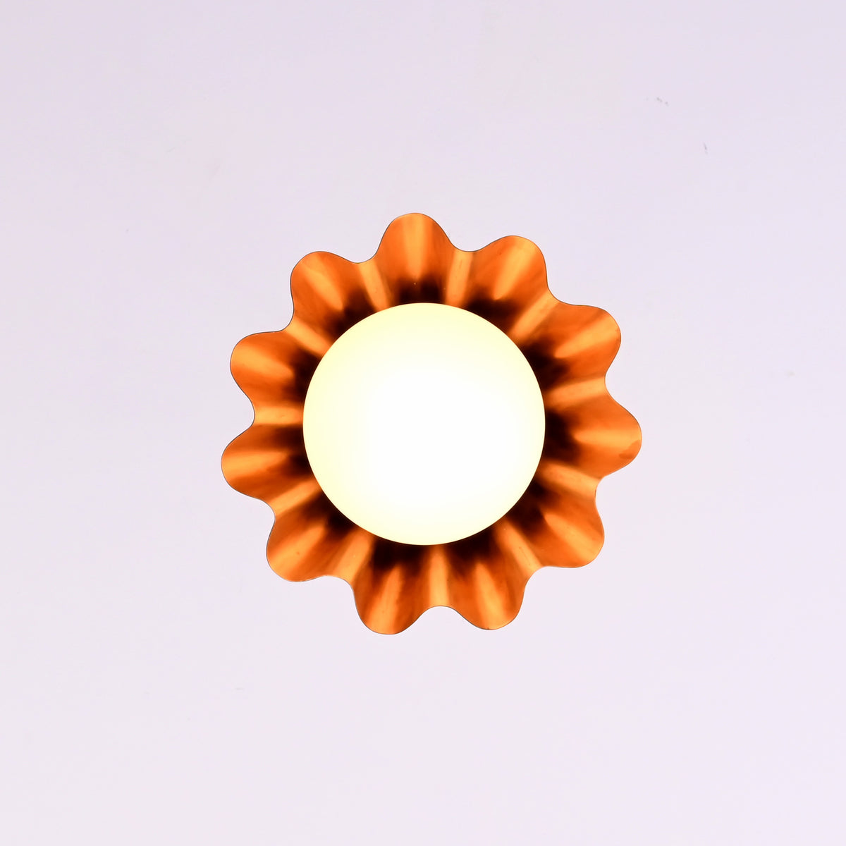 Bottom view of modern brass fluted disc pendant light with glowing glass globe and warm ambient illumination.