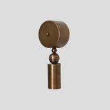 Brass geometric wall sconce with cylindrical base and spherical accent, modern handmade lighting fixture angled view