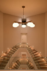 Brass oval glass ball chandelier installed in a warm interior with five glowing opal shades and balanced linear design