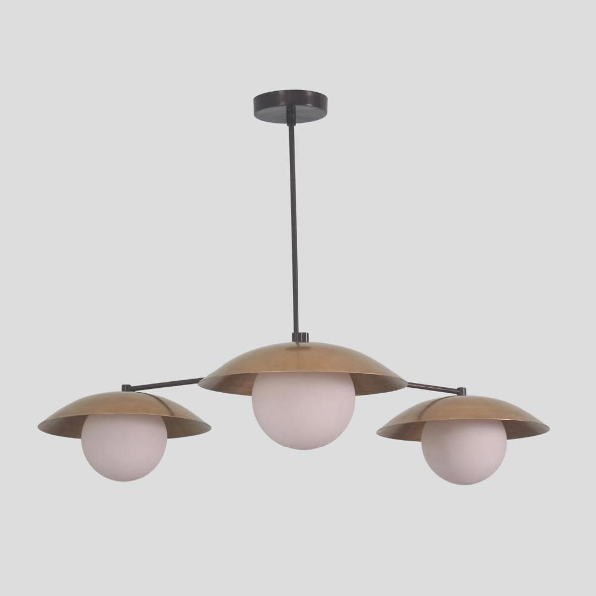 Modern pendant chandelier with three spherical globe lights and dome brass shades, blending industrial and minimalist style.
