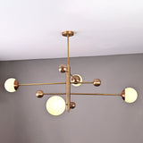 Angled view of modern brushed brass chandelier featuring four opal glass globes on minimalist linear arms.