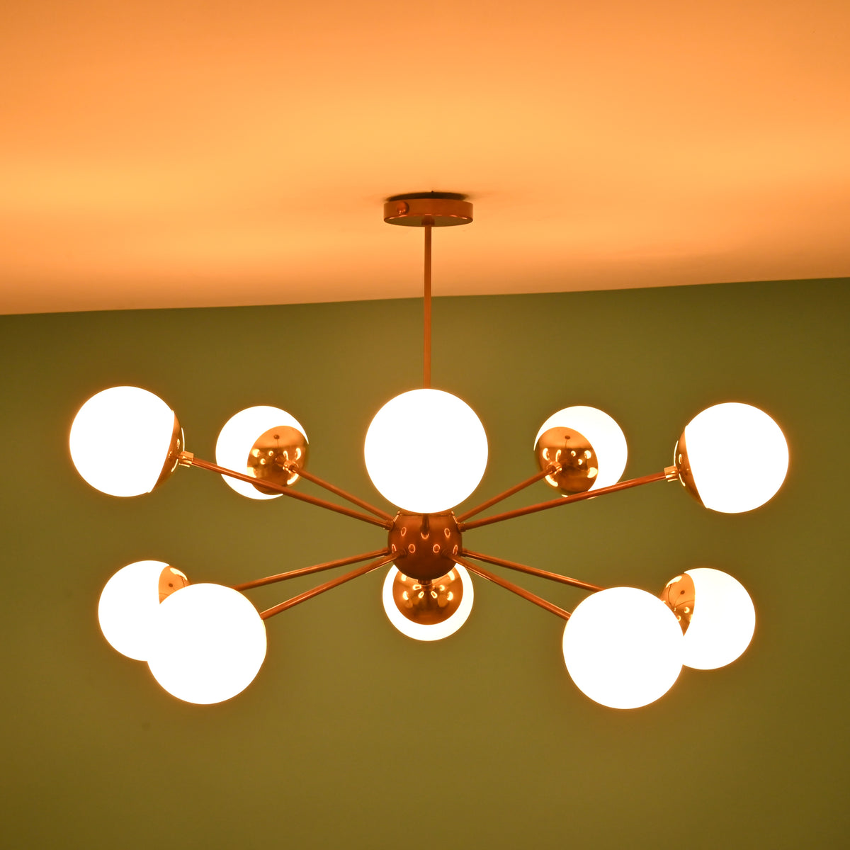 Bottom view of a handcrafted brass globe chandelier showing central hub detailing and evenly spaced light arms.