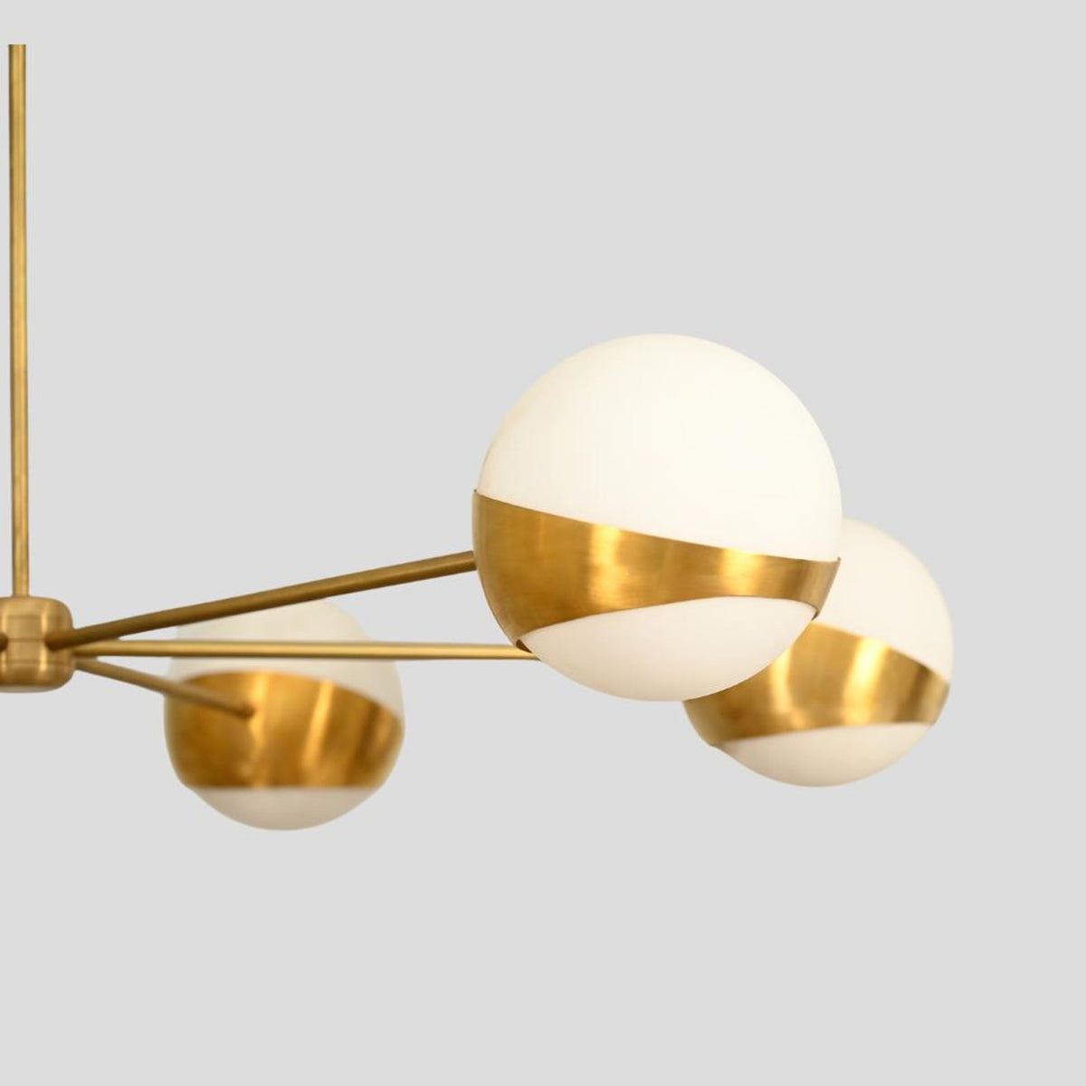 Close-up of brass chandelier globe shade, opal glass and brushed brass detail.