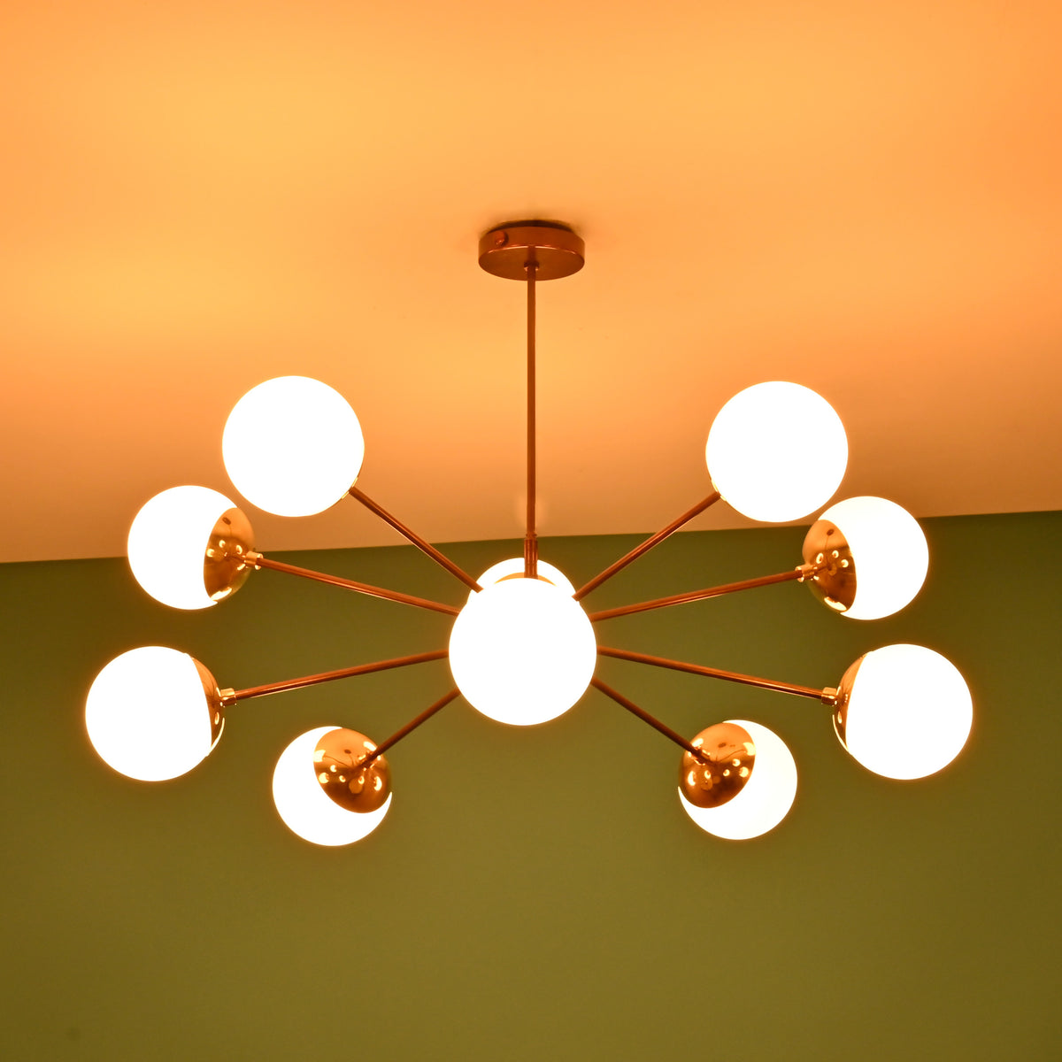 Modern brass globe chandelier illuminated with warm ambient lighting, ideal for dining rooms and living spaces.