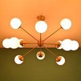 Modern brass chandelier with glowing globes against a warm ceiling