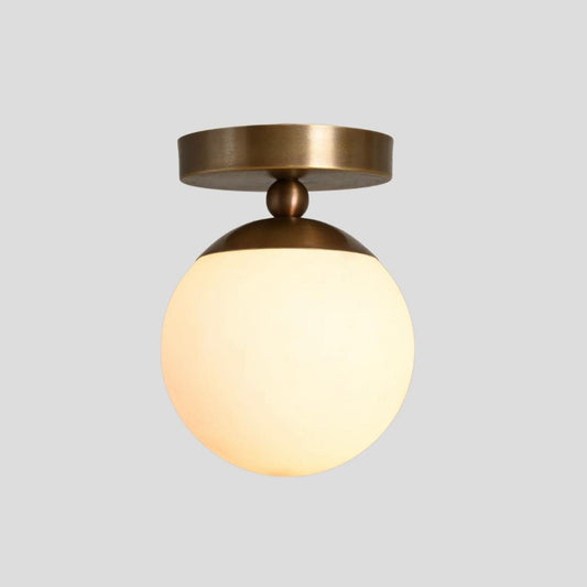 Brass flush mount ceiling fixture with illuminated opal glass globe – warm ambient lighting for modern interiors