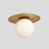 Side view of brass flush mount ceiling light with frosted glass globe and decorative fluted brass plate