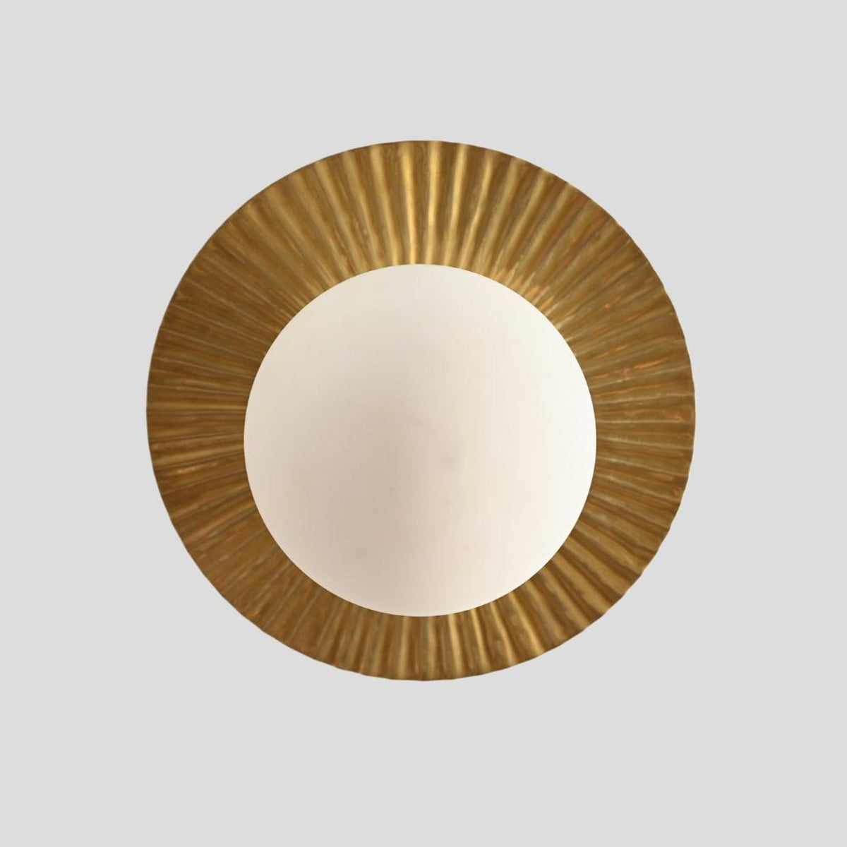 Top view of brass flush mount ceiling light with circular fluted brass plate and frosted glass globe