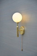 Close-up of polished brass globe wall light with white opal glass shade and sleek cylindrical arm