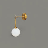 Angled close-up of brass globe wall light showing round base and suspended glass globe shade