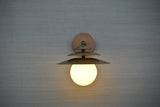 Front view of brass wall sconce with layered shades and globe diffuser, handmade modern lighting by Brass Leaf Studio
