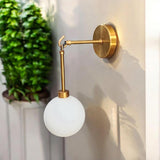 Modern brass wall sconce with frosted glass globe mounted on beige wall – handcrafted lighting by Brass Leaf Studio