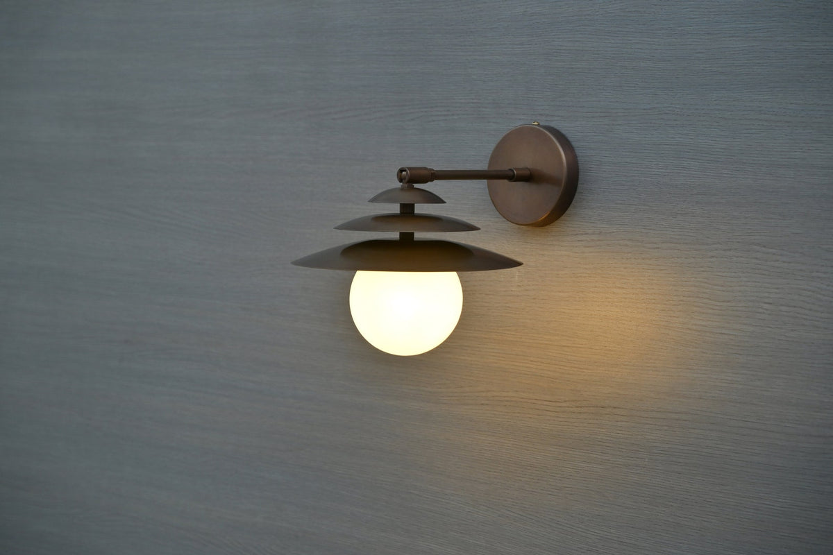 Modern brass globe wall sconce with layered design mounted on wall, ideal for living rooms, cafes, and entryways