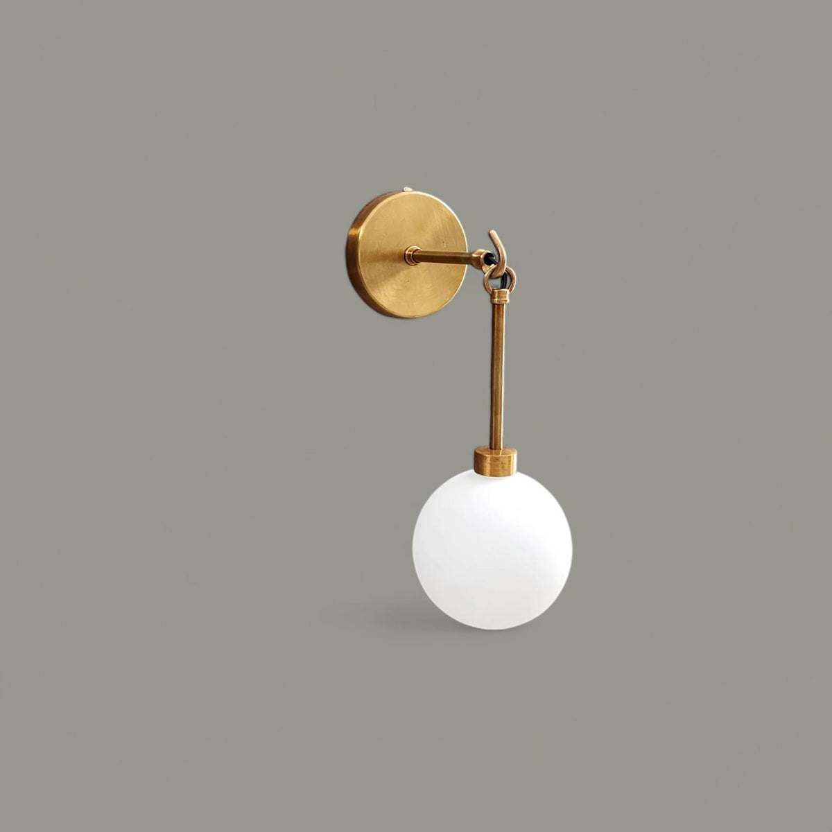 Side view of handmade brass wall sconce with frosted glass globe – minimalist modern wall light