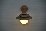 Top view of brass wall sconce showcasing layered disc shades and spherical globe light