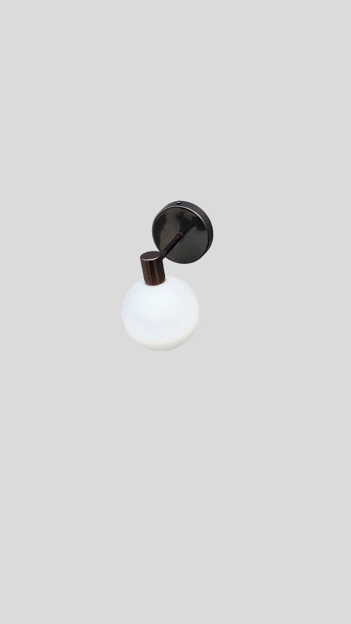 Handmade brass globe wall light featuring opal glass shade and black backplate