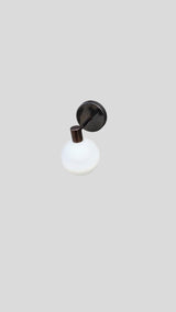 Handmade brass globe wall light featuring opal glass shade and black backplate