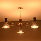 Warm-lit 3-light brass chandelier with cone shades, handcrafted in a mid-century modern industrial style.
