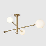Side angle of 3-light brass ceiling chandelier with white glass globes and modern flushmount design.