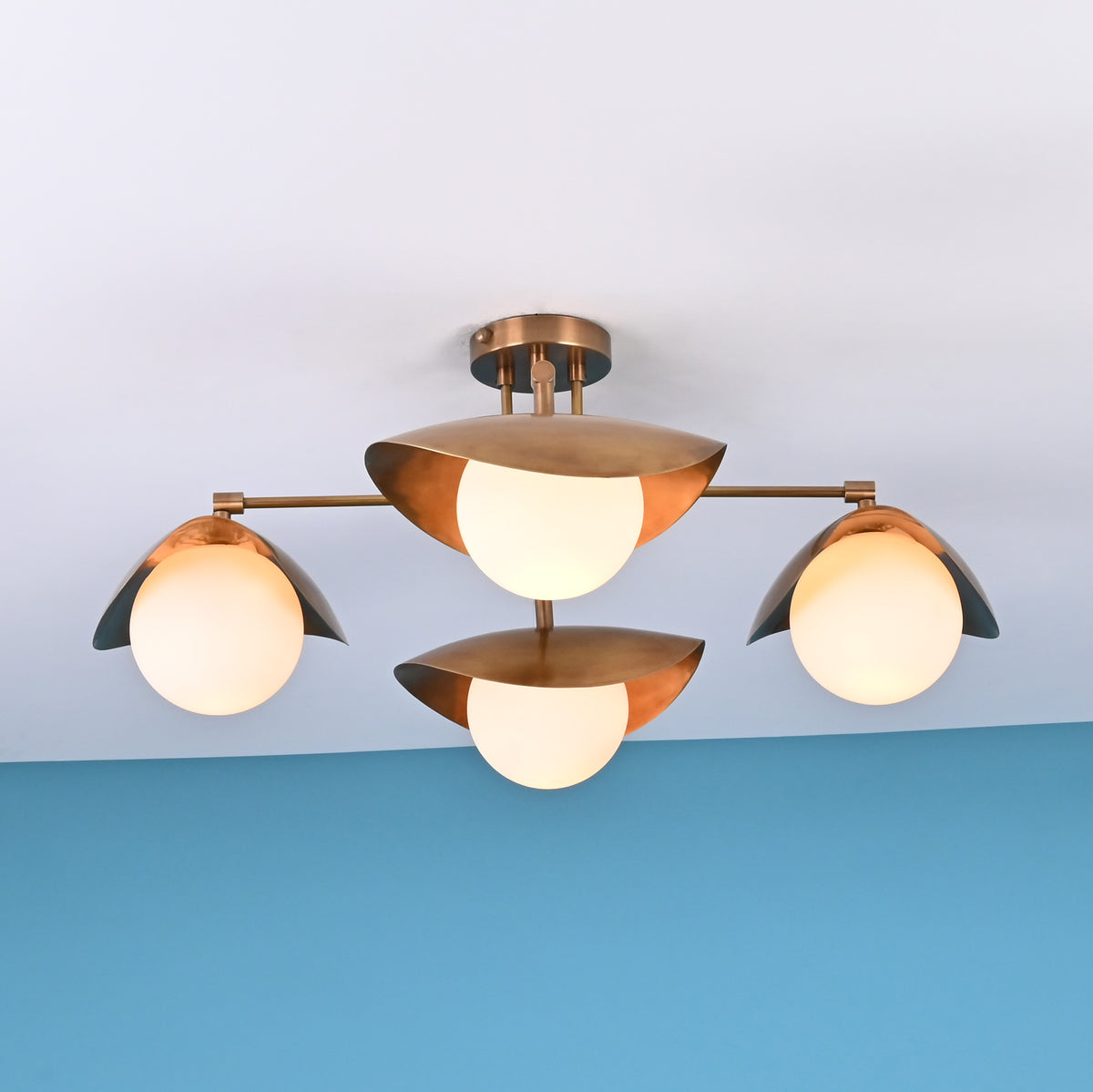Front view of 4 light brass flush mount ceiling fixture with opal globe shades and sculpted bowl design