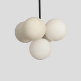 Close-up view of frosted globe shades on handcrafted brass 5-light chandelier – Brass Leaf Studio