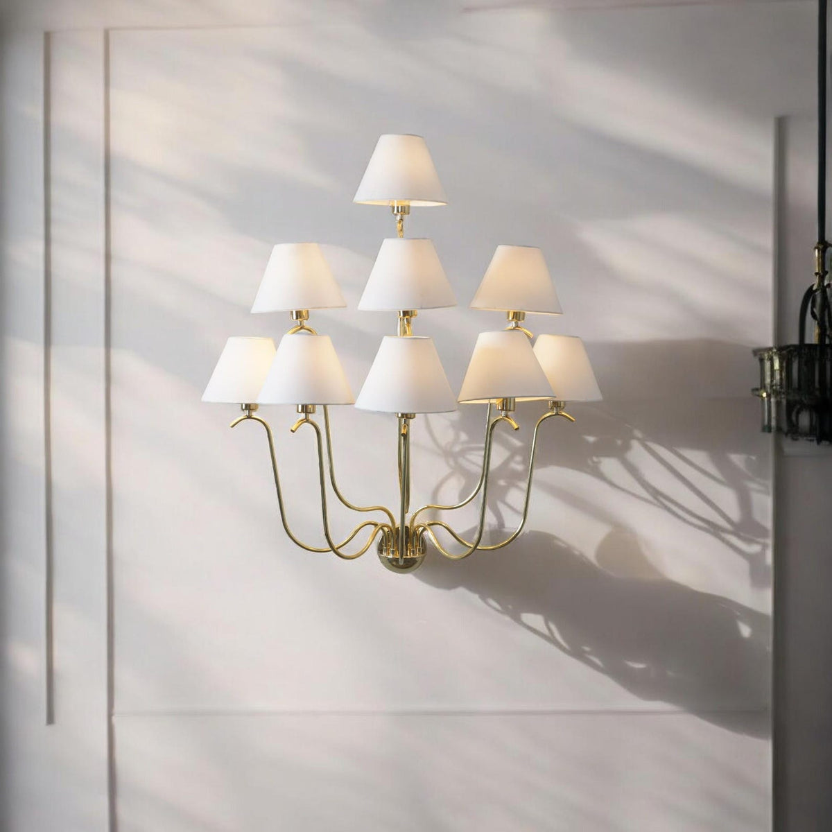 Brass Leaf Studio nine-light brass chandelier with white fabric shades illuminating a refined contemporary living space.