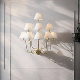 Brass Leaf Studio nine-light brass chandelier with white fabric shades illuminating a refined contemporary living space.