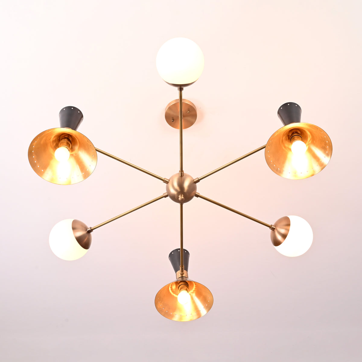 Top-down view of a 9-light brass chandelier showcasing cone shades and glowing bulbs in a star-like arrangement.